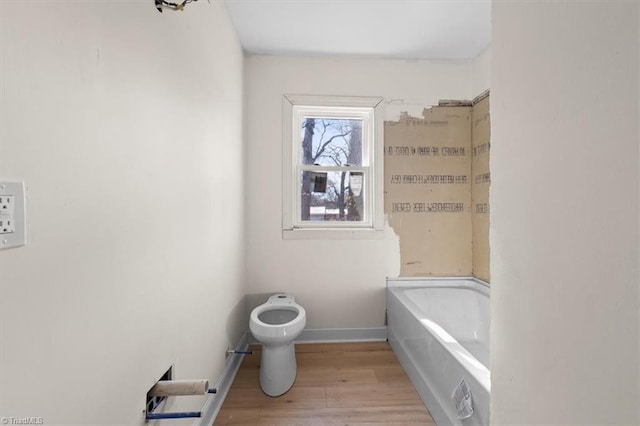 bathroom featuring wood-type flooring, a bathtub, and toilet