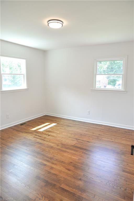 empty room featuring a healthy amount of sunlight and dark hardwood / wood-style floors