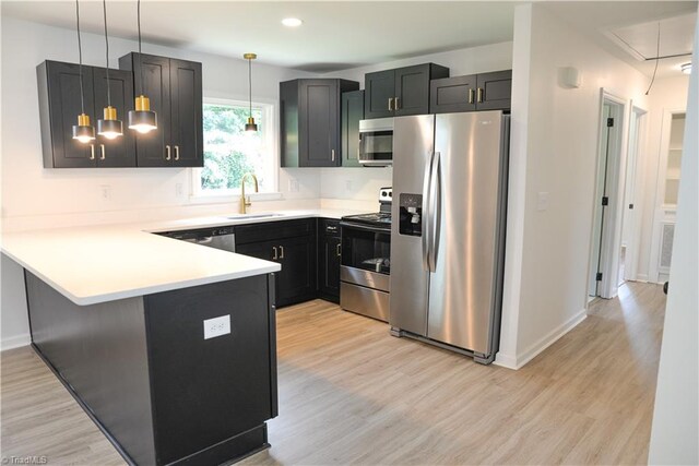 kitchen featuring pendant lighting, stainless steel appliances, kitchen peninsula, and light hardwood / wood-style floors