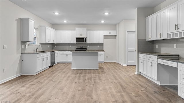 233 Lisa Ln, Winston-Salem, NC 27107 - kitchen featuring appliances with stainless steel finishes, decorative backsplash, baseboards, light wood finished floors, and dark countertops