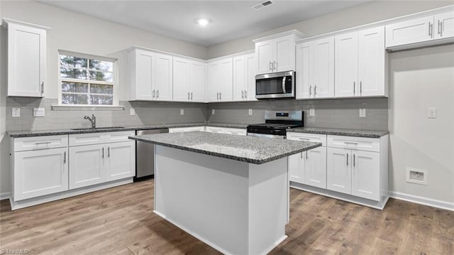 233 Lisa Ln, Winston-Salem, NC 27107 - kitchen featuring appliances with stainless steel finishes, white cabinets, stone counters, a center island, and decorative backsplash