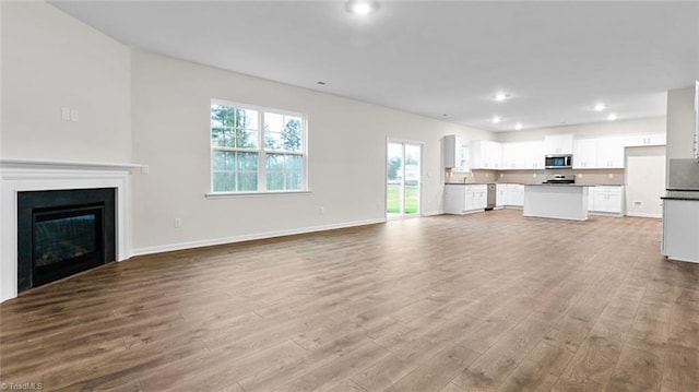 233 Lisa Ln, Winston-Salem, NC 27107 - unfurnished living room featuring wood finished floors, baseboards, recessed lighting, and a glass covered fireplace