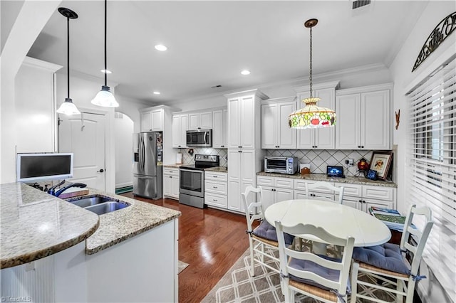 kitchen featuring light stone counters, sink, hanging light fixtures, and appliances with stainless steel finishes