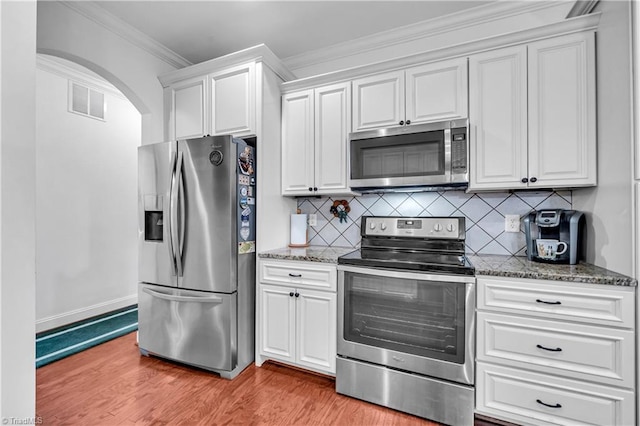 kitchen featuring tasteful backsplash, crown molding, light hardwood / wood-style floors, white cabinets, and appliances with stainless steel finishes