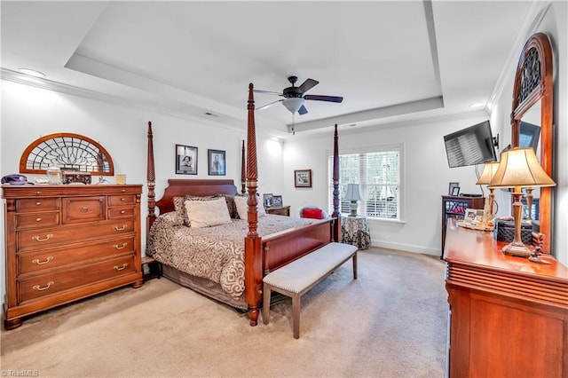 bedroom featuring a tray ceiling, crown molding, ceiling fan, and light colored carpet