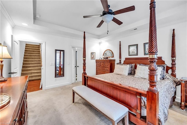 carpeted bedroom with a tray ceiling, ceiling fan, and crown molding