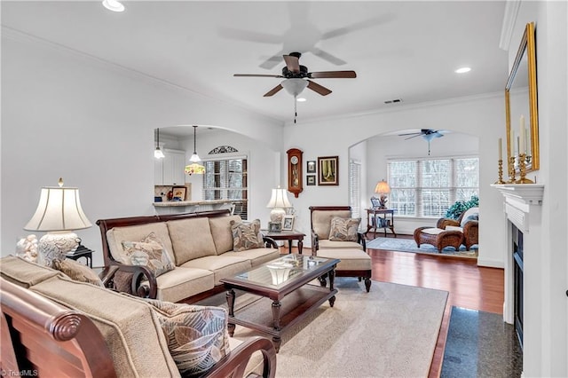 living room with ceiling fan, dark hardwood / wood-style flooring, and ornamental molding