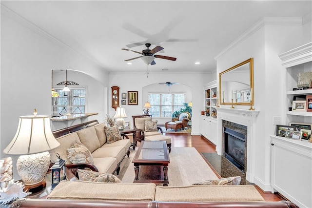 living room with dark hardwood / wood-style floors, built in features, ceiling fan, and crown molding