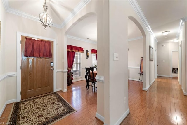 foyer entrance with a notable chandelier, ornamental molding, and light wood-type flooring