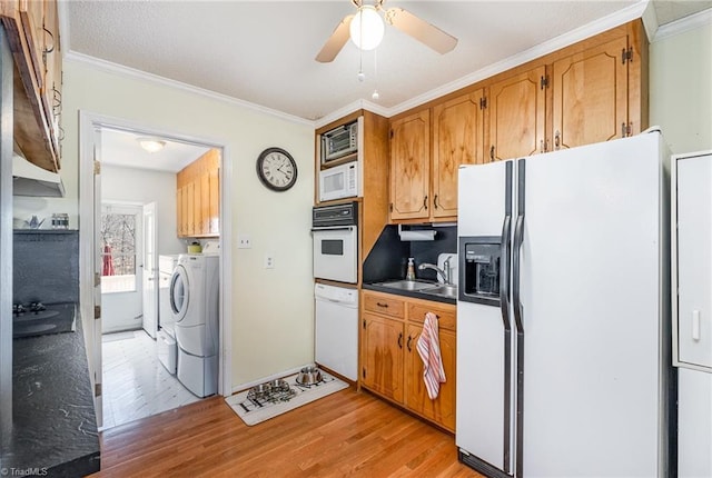 kitchen with white appliances, washing machine and dryer, crown molding, and light wood finished floors