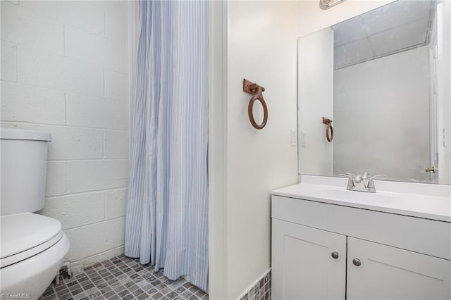 bathroom featuring concrete block wall, toilet, vanity, and a shower with curtain