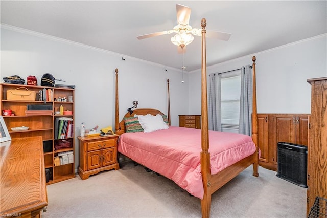 bedroom featuring a ceiling fan, light colored carpet, a wainscoted wall, and ornamental molding