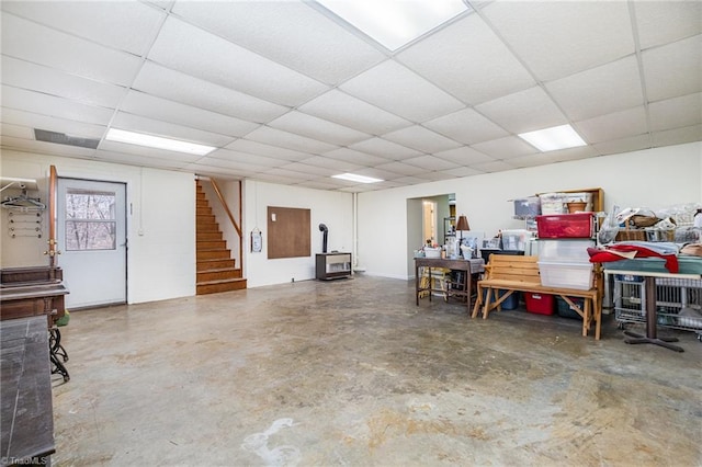 interior space with a drop ceiling, stairs, and a wood stove