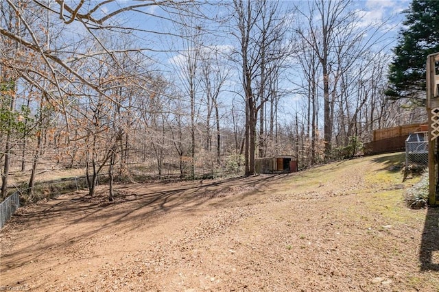 view of yard featuring a storage shed, an outdoor structure, and fence