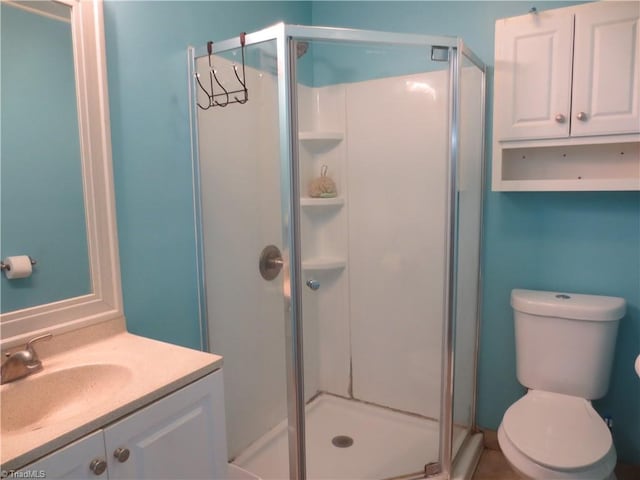 bathroom featuring a shower with door, vanity, and toilet