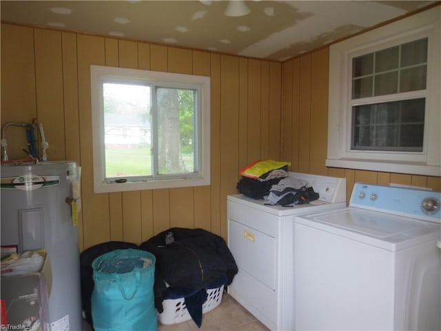 washroom featuring washing machine and clothes dryer, wooden walls, and water heater