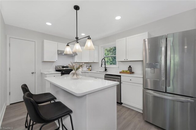 4420 Chebar Dr, Pfafftown, NC 27040 - kitchen featuring appliances with stainless steel finishes, a kitchen breakfast bar, white cabinets, wood finished floors, and range hood