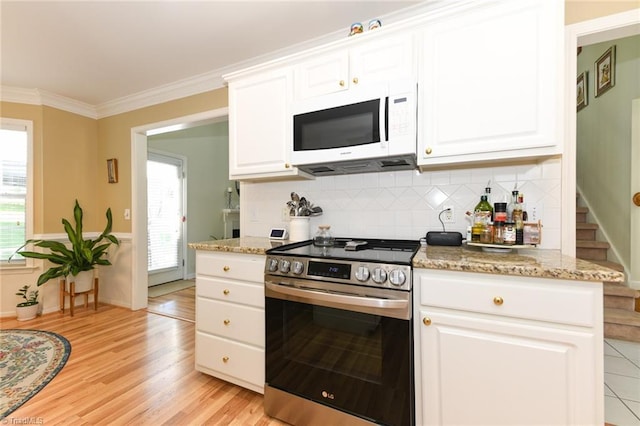 kitchen featuring white microwave, stainless steel electric range oven, white cabinetry, tasteful backsplash, and ornamental molding