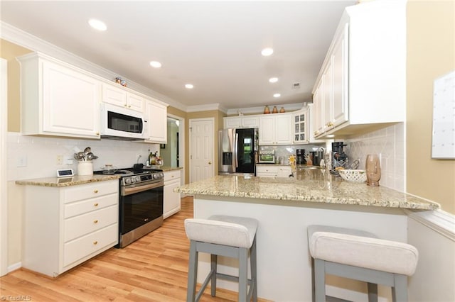 kitchen with stainless steel appliances, a peninsula, decorative backsplash, ornamental molding, and a kitchen bar