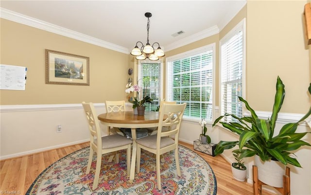 dining space featuring wood finished floors, a chandelier, crown molding, and baseboards