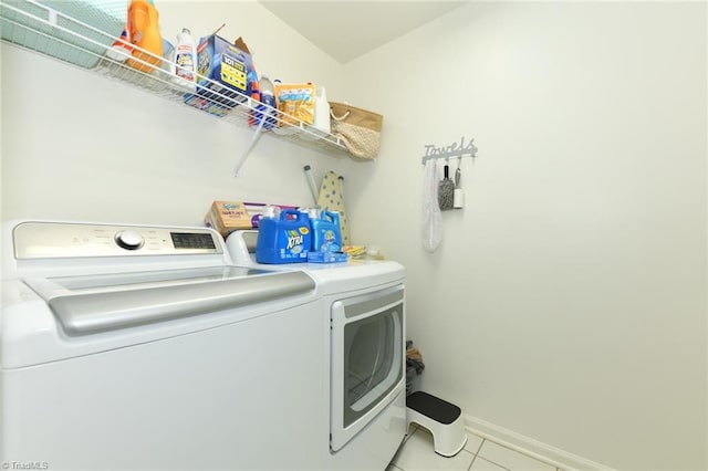 clothes washing area with washer and clothes dryer, tile patterned floors, and baseboards