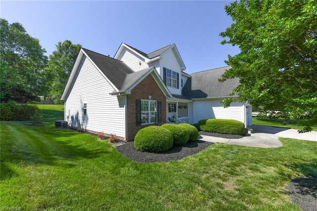 view of home's exterior with a yard, central AC unit, a shingled roof, and brick siding