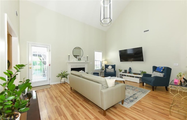 living room featuring high vaulted ceiling, light wood-style flooring, and a tile fireplace