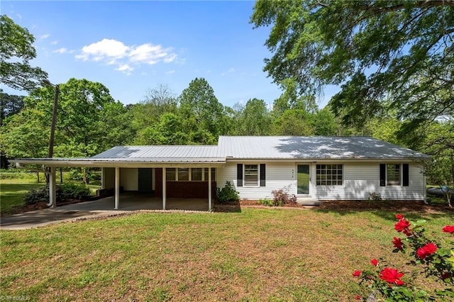 back of house featuring a lawn, driveway, an attached carport, and metal roof