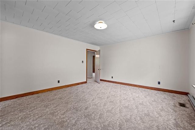 spare room with carpet floors, visible vents, and baseboards