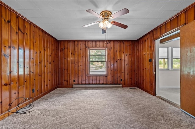 carpeted empty room featuring a baseboard heating unit, ceiling fan, baseboards, and a healthy amount of sunlight