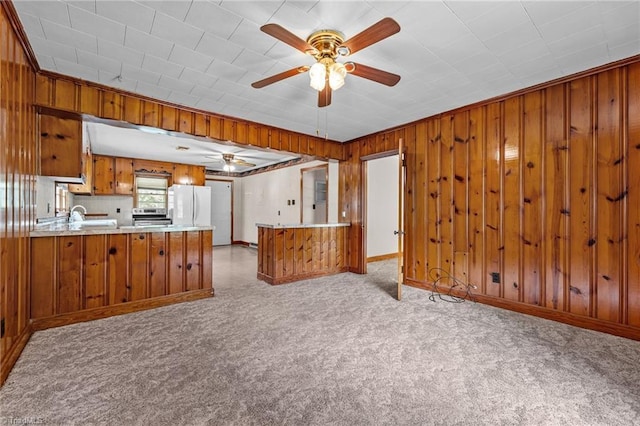 kitchen featuring brown cabinets, ceiling fan, light colored carpet, a peninsula, and freestanding refrigerator