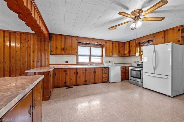 kitchen featuring stainless steel electric range oven, freestanding refrigerator, brown cabinets, and washer / dryer