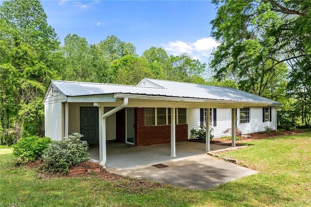 back of property featuring an attached carport, a yard, and metal roof