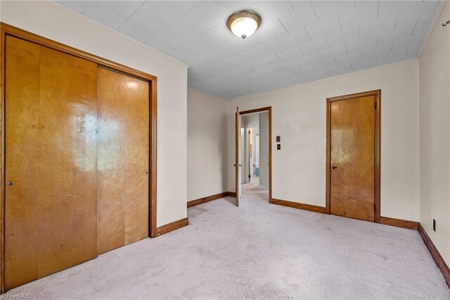unfurnished bedroom with light colored carpet, baseboards, and a closet