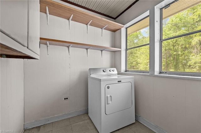 clothes washing area with washer / dryer, cabinet space, and light tile patterned floors
