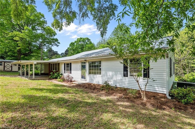 rear view of house featuring an outbuilding, a yard, a patio, metal roof, and a storage unit