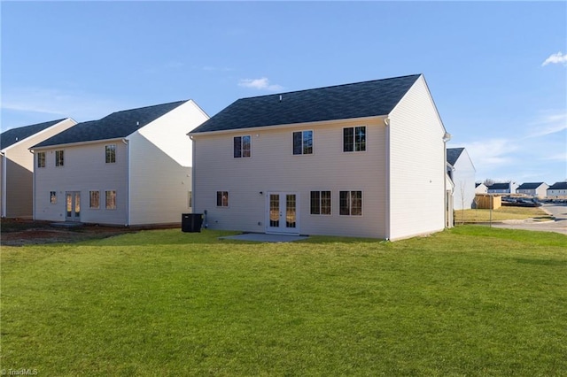 back of property with french doors, a lawn, and central AC