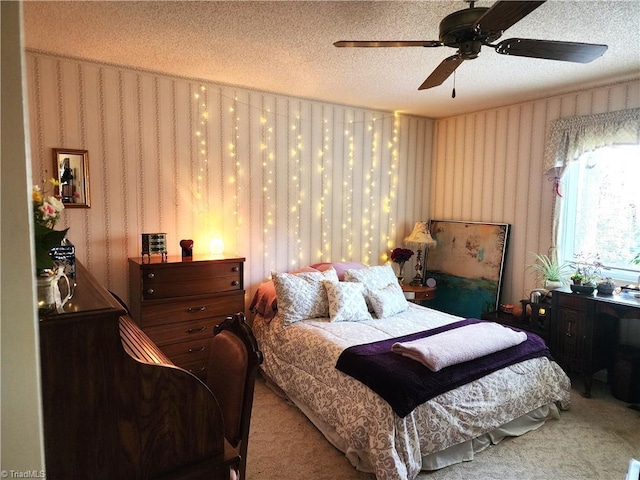 carpeted bedroom with a textured ceiling, ceiling fan, and wallpapered walls