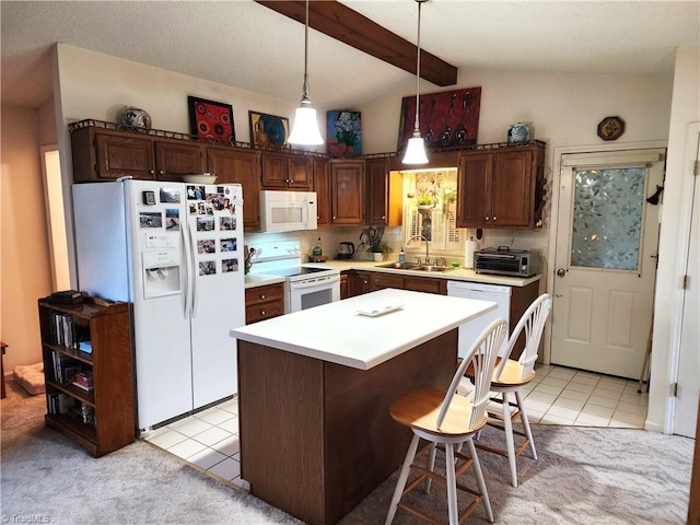 kitchen with white appliances, a kitchen island, light countertops, pendant lighting, and a sink