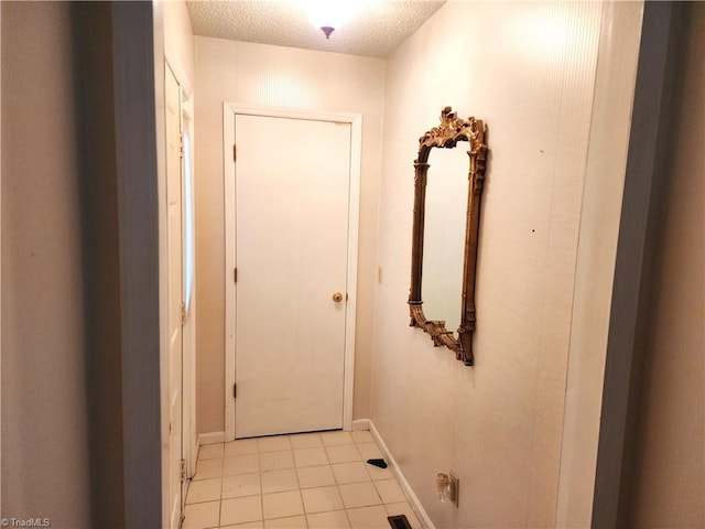 doorway to outside with a textured ceiling and baseboards