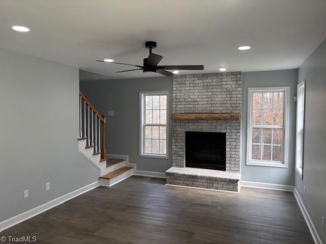 unfurnished living room featuring ceiling fan, dark wood-type flooring, and a brick fireplace