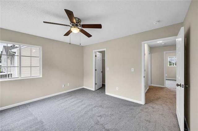 unfurnished bedroom featuring a closet, carpet flooring, a walk in closet, and ceiling fan