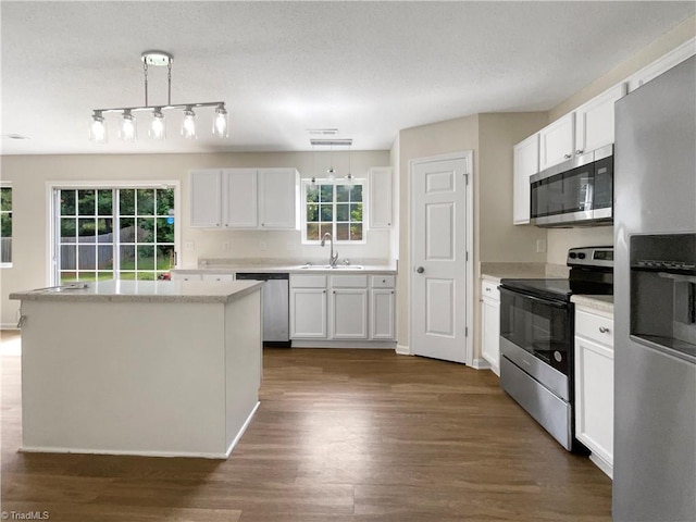 kitchen featuring appliances with stainless steel finishes, dark wood-type flooring, white cabinets, and a healthy amount of sunlight