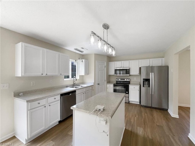 kitchen featuring hanging light fixtures, sink, white cabinets, and stainless steel appliances