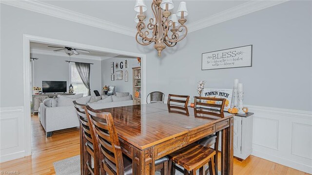 dining space with light hardwood / wood-style floors, ceiling fan with notable chandelier, and ornamental molding