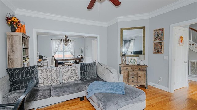 living room featuring hardwood / wood-style flooring, ceiling fan with notable chandelier, and ornamental molding