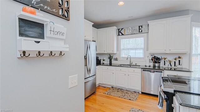 kitchen with sink, white cabinets, stainless steel appliances, and light hardwood / wood-style floors