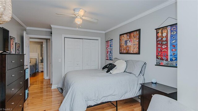 bedroom with ceiling fan, light hardwood / wood-style floors, ornamental molding, and a closet