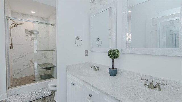 bathroom with wood-type flooring, vanity, a shower with shower door, and toilet