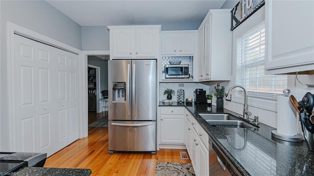 kitchen featuring backsplash, white cabinets, sink, light hardwood / wood-style flooring, and stainless steel appliances